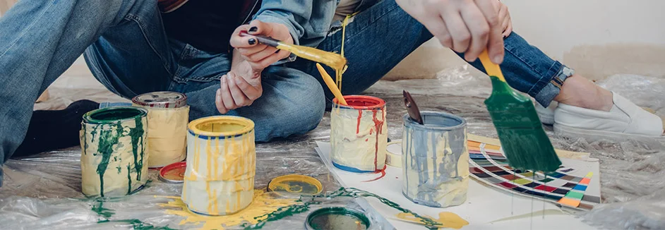 Personen sitzen beim streichen auf dem Boden